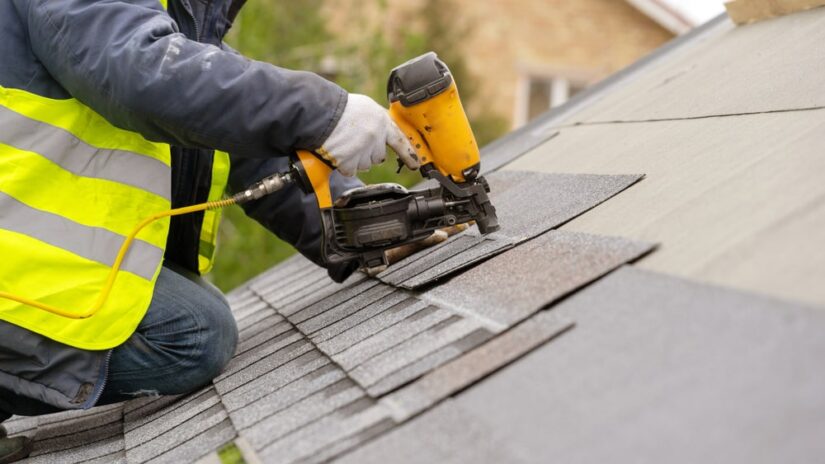 Worker Nailing Shingles To The Roof